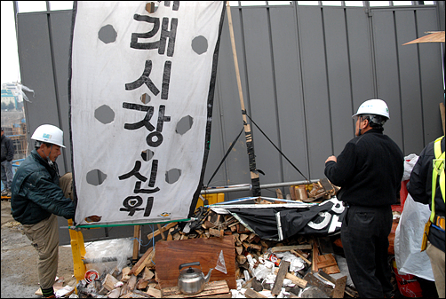 침탈과 몸싸움 끝에 주민대책위의 농성장을 확보한 시공업체 직원들이 농성장을 해체 부수고 있다. 재래시장 신위를 뜯고 있는 시공업체 직원. 